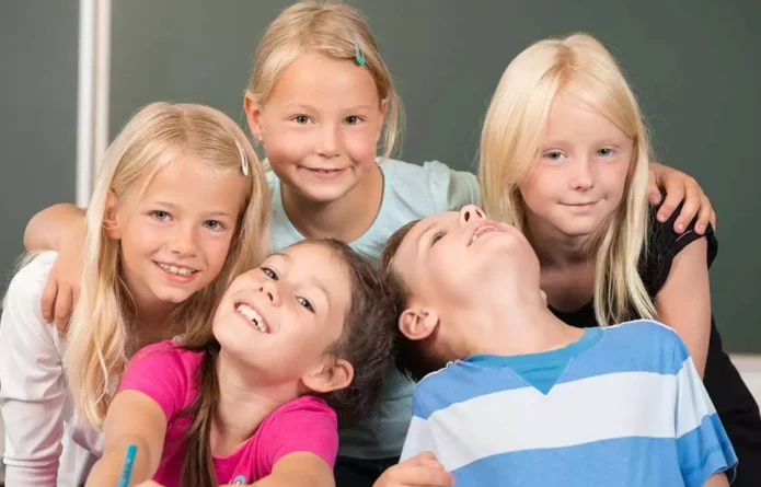 Eine Gruppe fröhlicher Schulkinder in einem Klassenzimmer, symbolisch für die Vorteile der Kinesiologie bei der Überwindung von Lernproblemen und Stress.